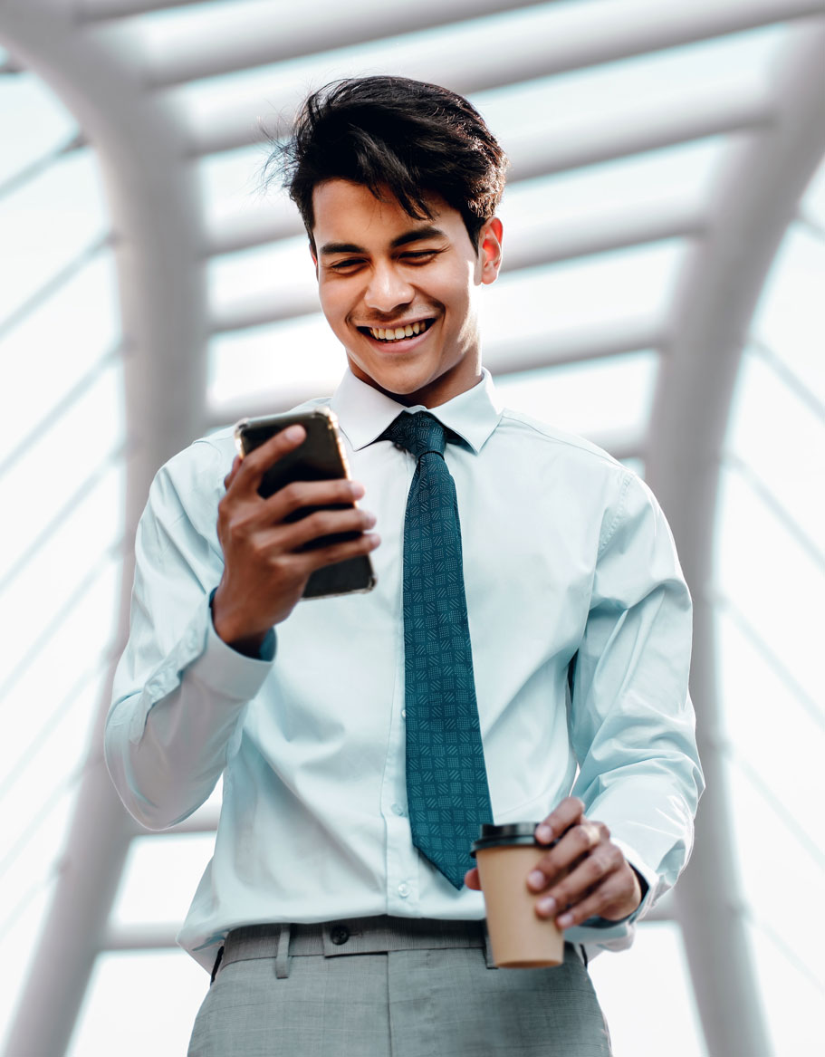 Man carrying coffee looking at phone